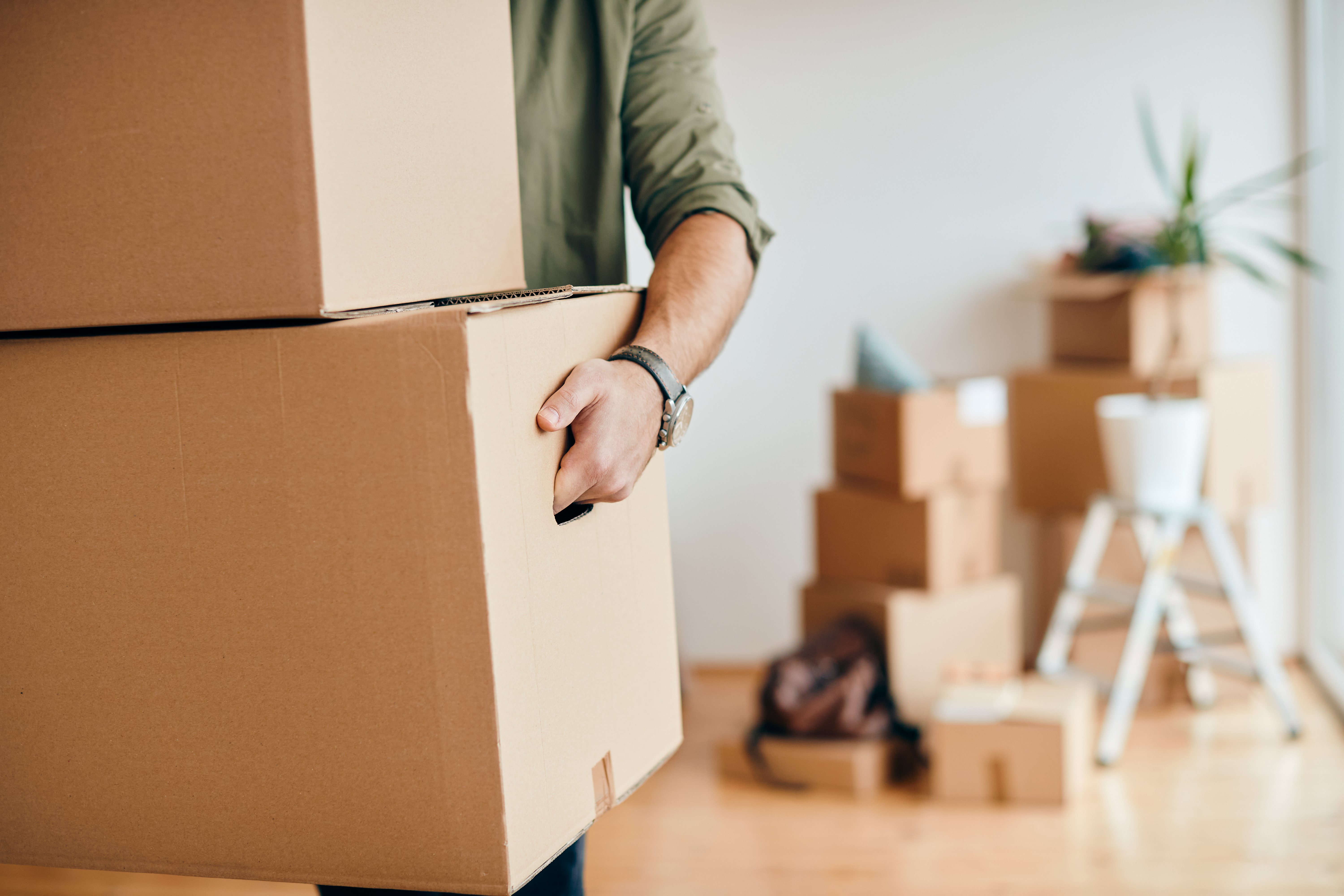 Close up of man carrying cardboard boxes while relocating into n